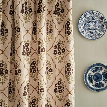 kitchen sitting room with french windows going out to the garden upholstered with beautiful floral curtains by molly mahon.  Poppy mustard sky design hand block printed and finished off with a molly mahon cushion in seed mustard